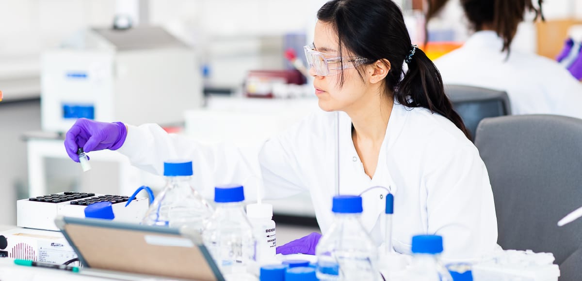 Pharmaceutical expert wearing a lab coat looking at samples in a lab 