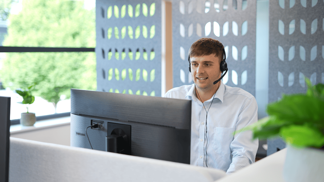 Man-sat-at-computer-wearing-a-headset